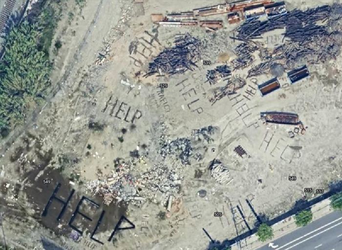Aerial view showing mysterious "Help" signs marked on the ground, fueling wild conspiracy theories. Aerial view showing mysterious "Help" signs marked on the ground, fueling wild conspiracy theories.