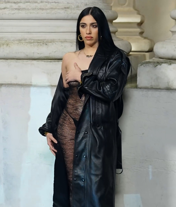 Lourdes Leon in a see-through bodysuit and leather coat, striking a pose against a stone wall. Lourdes Leon in a see-through bodysuit and leather coat, striking a pose against a stone wall.