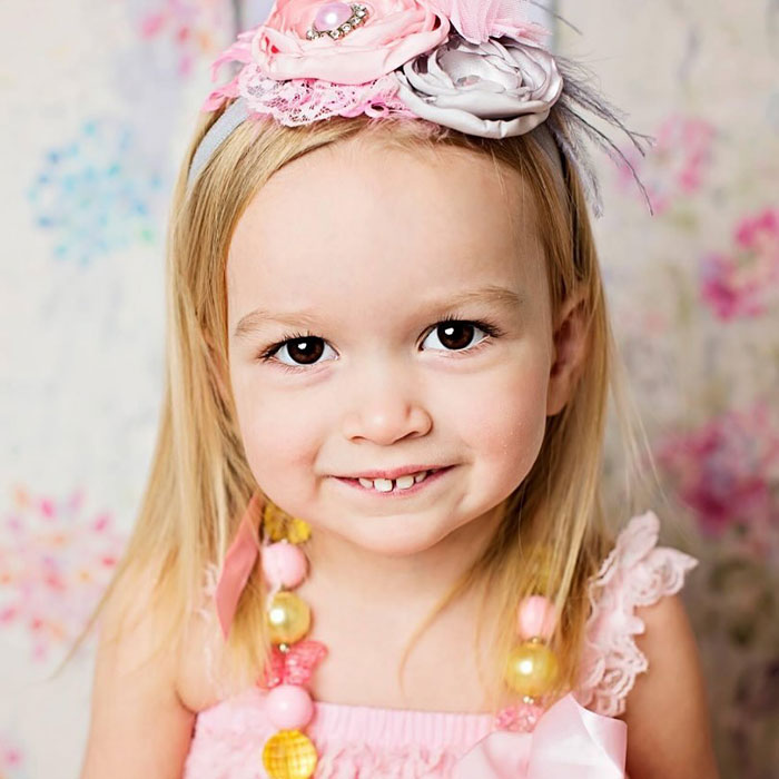 Young girl smiling, wearing a floral headband and colorful necklace, related to the Side-Eyeing Chloe meme. Young girl smiling, wearing a floral headband and colorful necklace, related to the Side-Eyeing Chloe meme.