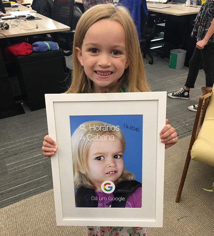 Girl holding a framed image of "Side-Eyeing Chloe" meme in an office setting. Girl holding a framed image of "Side-Eyeing Chloe" meme in an office setting.
