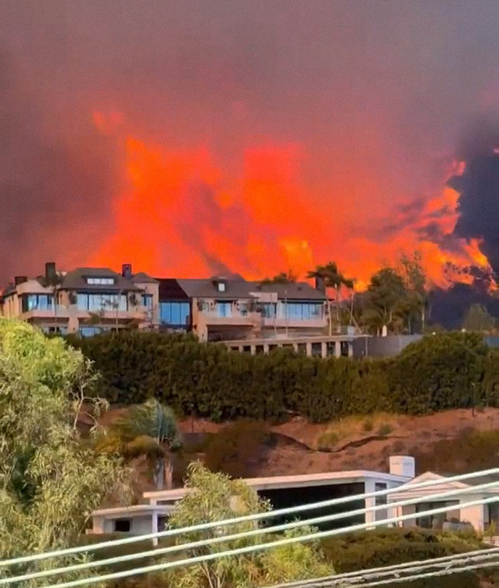 LA wildfires blaze behind homes. LA wildfires blaze behind homes.