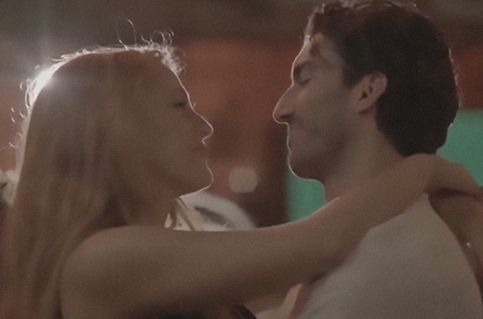 Two people embrace closely, smiling at each other; dimly lit background. Two people embrace closely, smiling at each other; dimly lit background.