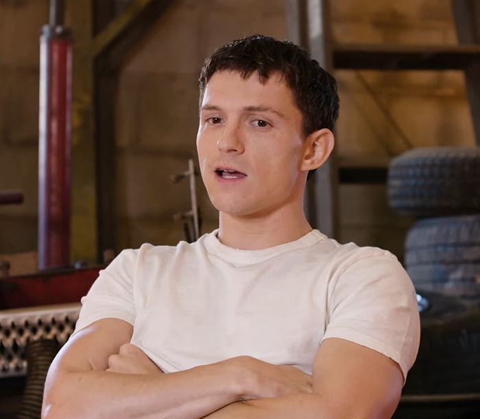 Tom Holland in a white shirt, speaking in a workshop setting. Tom Holland in a white shirt, speaking in a workshop setting.