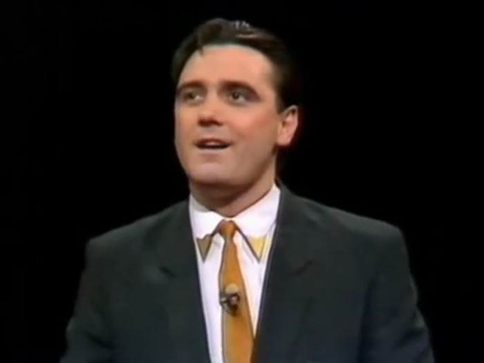 Tony Slattery from 'Whose Line Is It Anyway?', wearing a suit and tie, appearing on stage. Tony Slattery from 'Whose Line Is It Anyway?', wearing a suit and tie, appearing on stage.