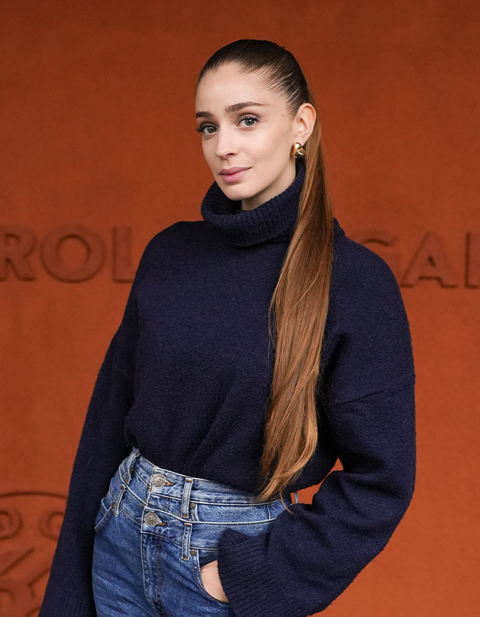 Ballerina posing against orange background, wearing a navy sweater and jeans. Ballerina posing against orange background, wearing a navy sweater and jeans.