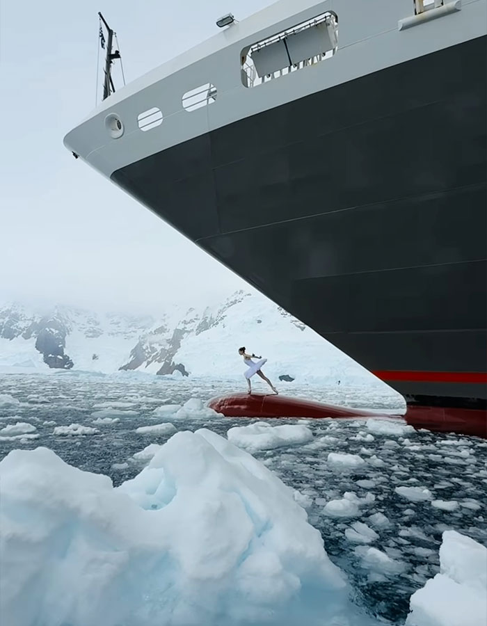 Ballerina dances on ship's bow in Antarctica, amidst icy waters, showcasing career-ending danger. Ballerina dances on ship's bow in Antarctica, amidst icy waters, showcasing career-ending danger.