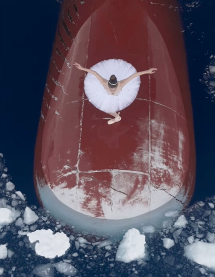 Ballerina performing on ship's bow in Antarctica, surrounded by icy waters, showcasing career-ending danger. Ballerina performing on ship's bow in Antarctica, surrounded by icy waters, showcasing career-ending danger.