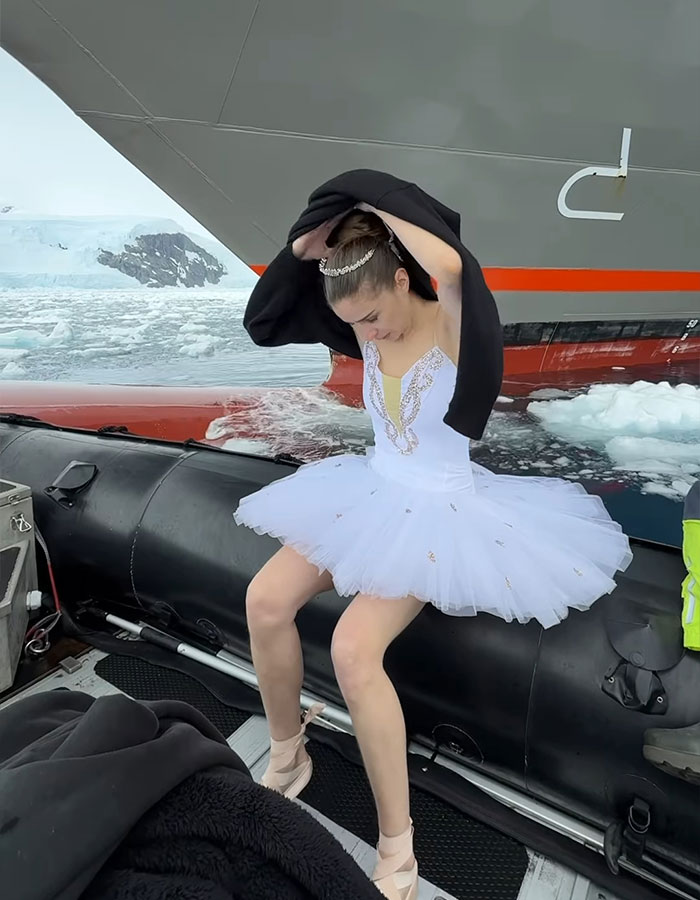 Ballerina wearing a tiara and tutu on a ship's bow in Antarctica waters, preparing to cover with a black jacket. Ballerina wearing a tiara and tutu on a ship's bow in Antarctica waters, preparing to cover with a black jacket.