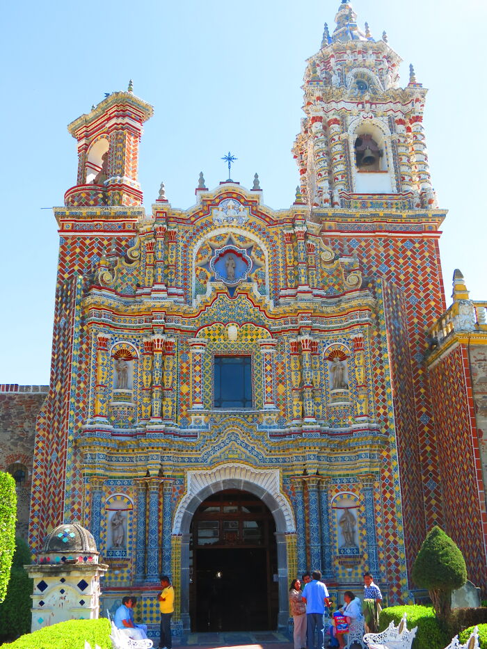 Ornate church facade with colorful tiles, showcasing fascinating architecture under a clear blue sky.