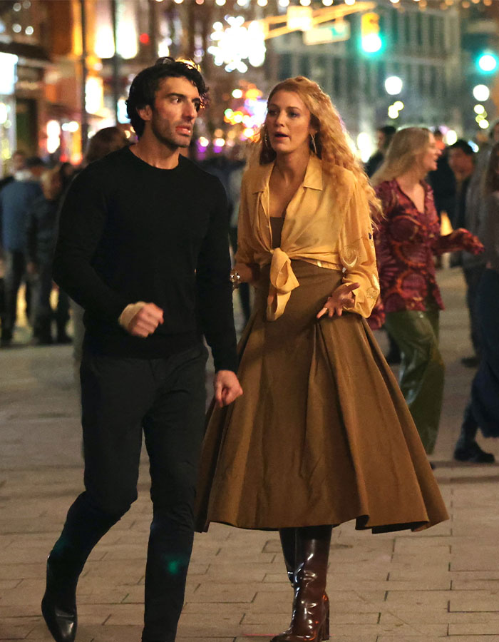 Justin Baldoni and a woman walking at night, discussing a legal matter downtown. Justin Baldoni and a woman walking at night, discussing a legal matter downtown.