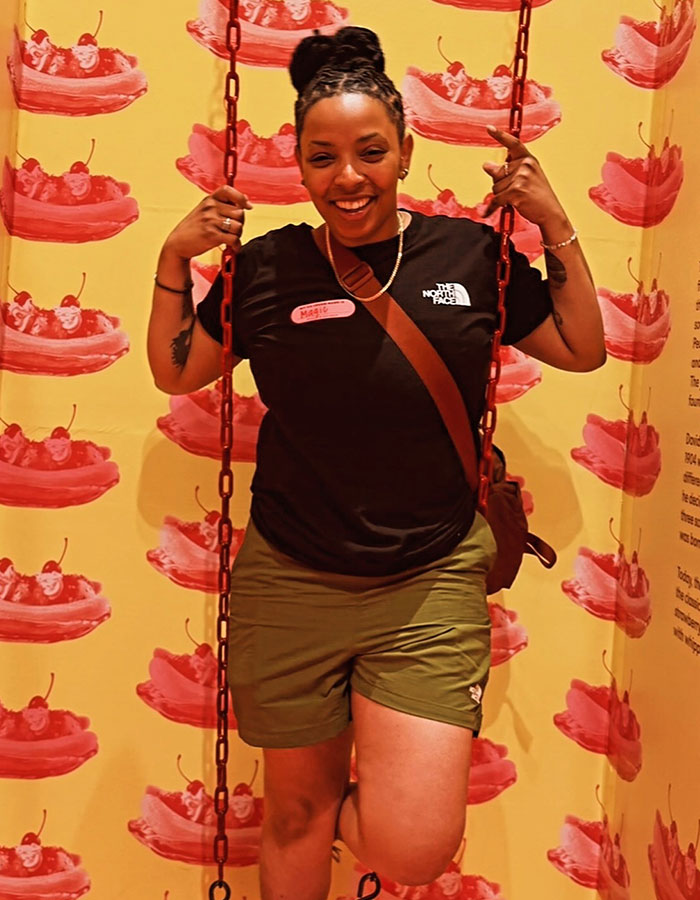 Woman smiling and sitting on a swing against a backdrop with dessert illustrations. Woman smiling and sitting on a swing against a backdrop with dessert illustrations.