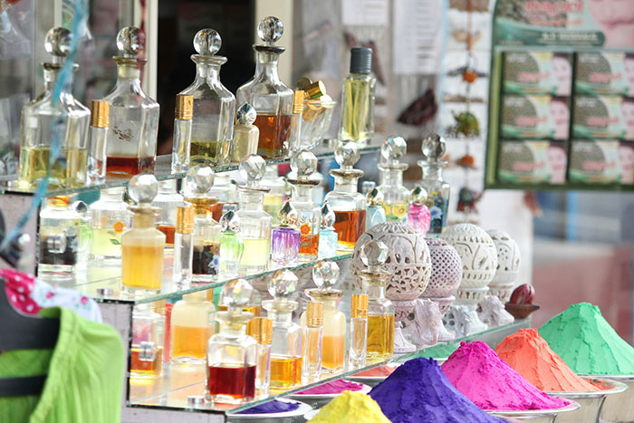 Perfume bottles on display with colorful powders in a market setting. Perfume bottles on display with colorful powders in a market setting.