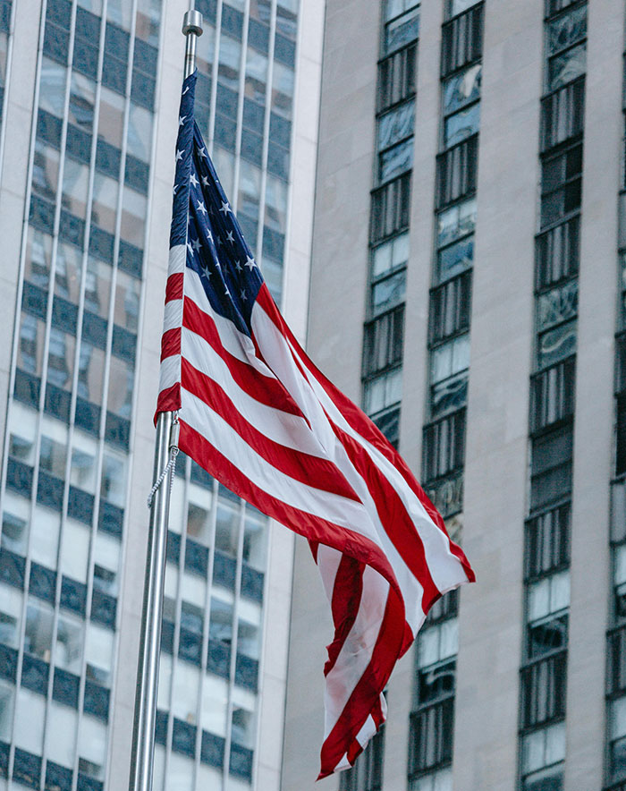 American flag waving in front of a tall building, symbolizing patriotism. American flag waving in front of a tall building, symbolizing patriotism.