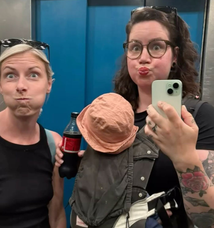 Two moms in an elevator making funny faces, one holding a soda bottle, redefining partying post-baby. Two moms in an elevator making funny faces, one holding a soda bottle, redefining partying post-baby.