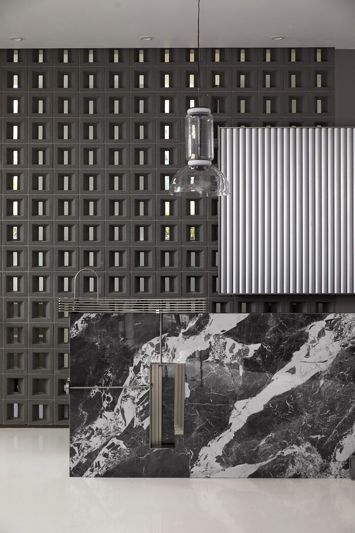 Stylish kitchen design showcasing a marble countertop, geometric wall, and modern lighting. Award-winning interior design.