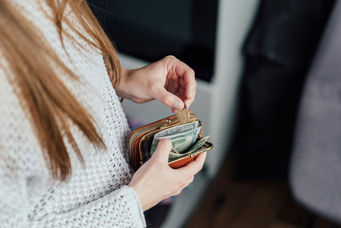 A babysitter holding a wallet, counting money after a last-minute favor. A babysitter holding a wallet, counting money after a last-minute favor.