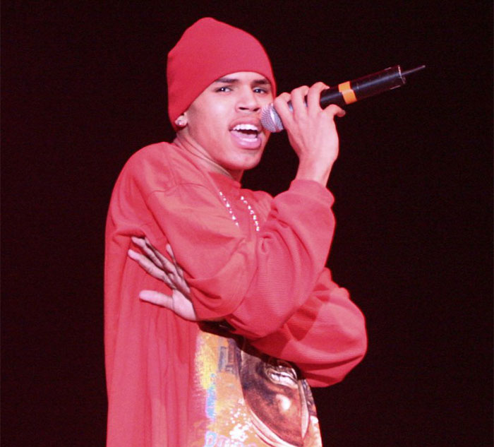 Singer performing on stage in a red outfit, holding a microphone, related to celebrity secrets.