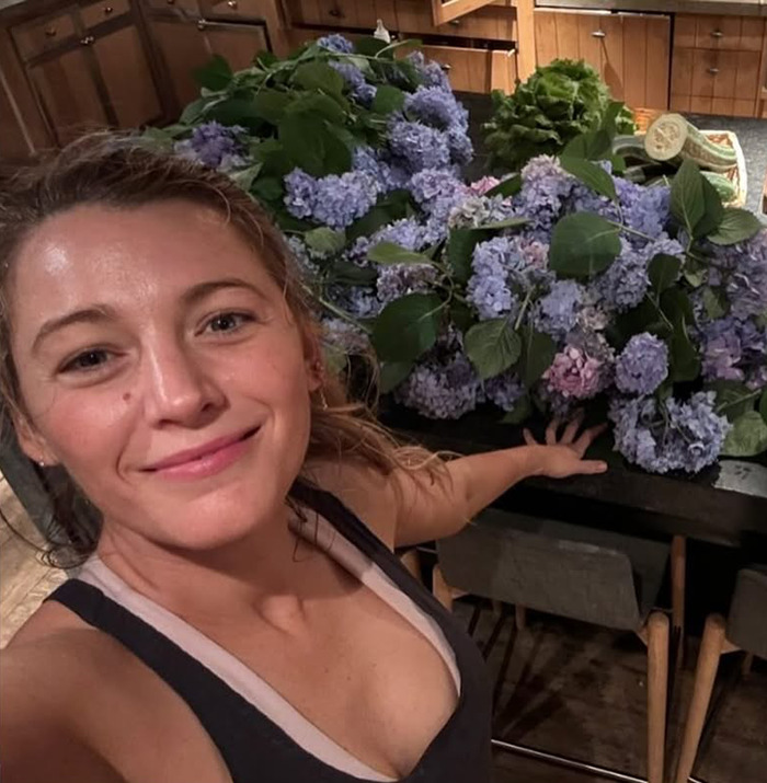 Blake Lively smiling with flowers behind her. Blake Lively smiling with flowers behind her.