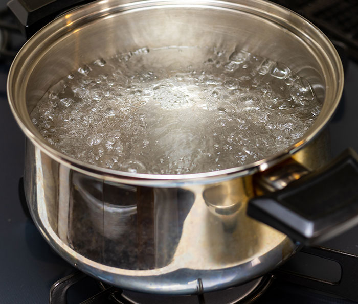 Boiling water in a metal pot on a stove, related to a sleepover prank incident. Boiling water in a metal pot on a stove, related to a sleepover prank incident.