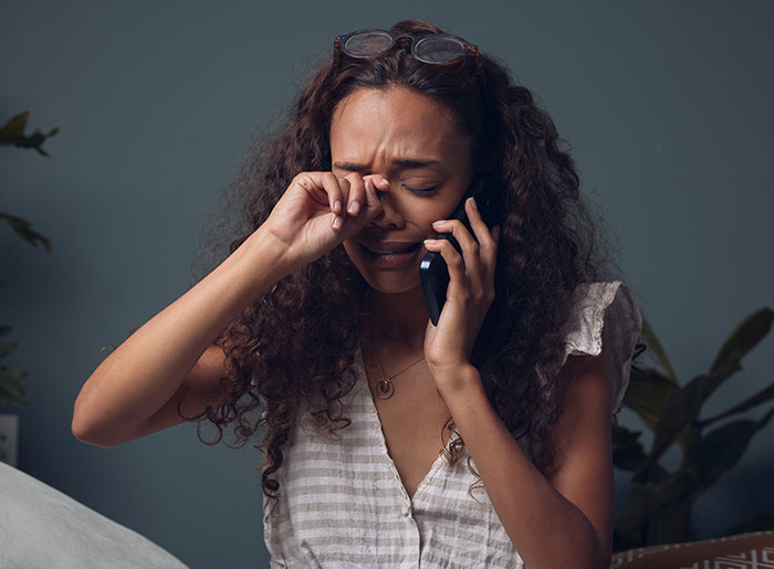 Woman crying on phone after not being invited to best friend's wedding. Woman crying on phone after not being invited to best friend's wedding.