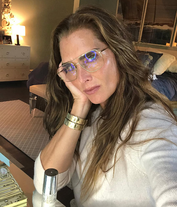 Brooke Shields wearing glasses sits indoors, resting her face on her hand, conveying contemplation. Brooke Shields wearing glasses sits indoors, resting her face on her hand, conveying contemplation.