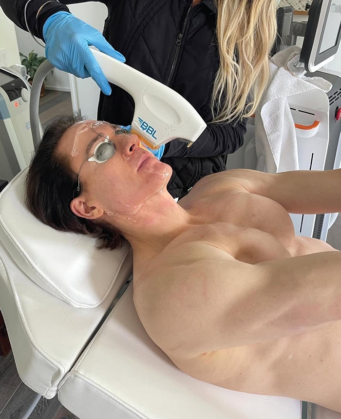 A man receiving a facial treatment, surrounded by equipment and wearing protective eyewear. A man receiving a facial treatment, surrounded by equipment and wearing protective eyewear.