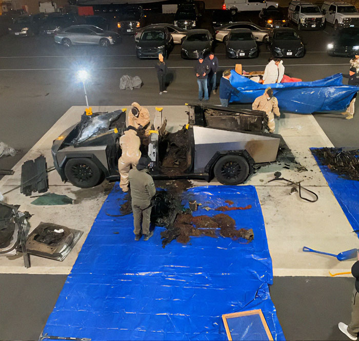Workers in protective suits inspect damaged Cybertruck after explosion incident. Workers in protective suits inspect damaged Cybertruck after explosion incident.