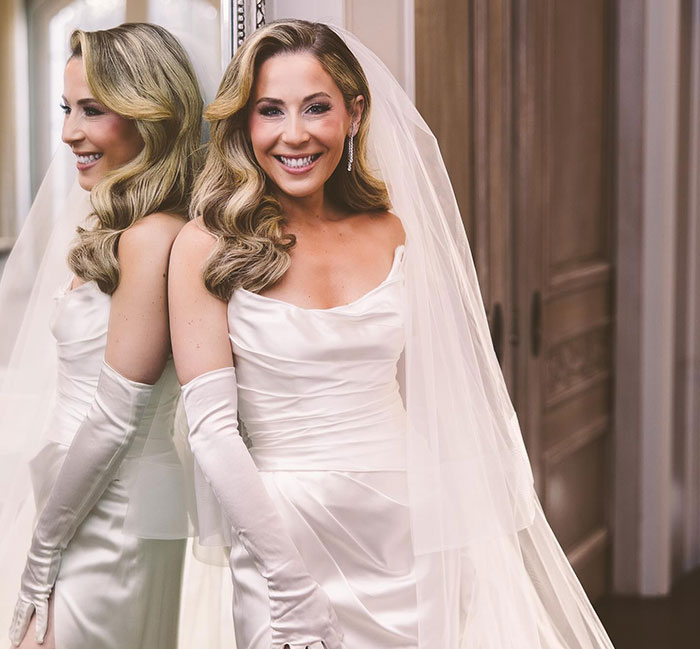 Blonde woman in wedding dress smiling at the mirror, capturing a School of Rock star moment. Blonde woman in wedding dress smiling at the mirror, capturing a School of Rock star moment.