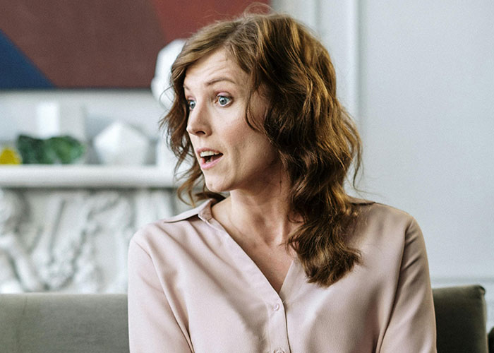 Woman in a blouse speaking, discussing the value of university education with an expressive gesture. Woman in a blouse speaking, discussing the value of university education with an expressive gesture.