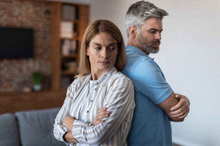 Young adult ignoring dad with arms crossed, symbolizing financial tension and family conflict. Young adult ignoring dad with arms crossed, symbolizing financial tension and family conflict.