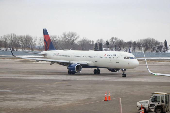 Delta airplane on a snowy tarmac, highlighting airline's role in urgent travel assistance. Delta airplane on a snowy tarmac, highlighting airline's role in urgent travel assistance.
