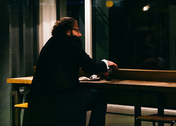 Person waiting alone at a restaurant table at night, looking out the window. Person waiting alone at a restaurant table at night, looking out the window.