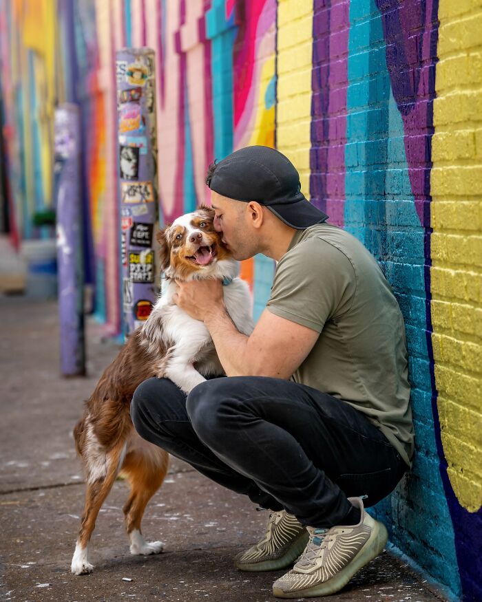 A man embraces a happy dog against a colorful NYC graffiti wall. A man embraces a happy dog against a colorful NYC graffiti wall.