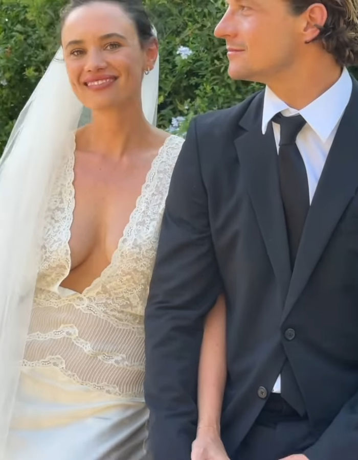 Australian bride in a lace wedding dress standing beside groom in a suit outdoors. Australian bride in a lace wedding dress standing beside groom in a suit outdoors.