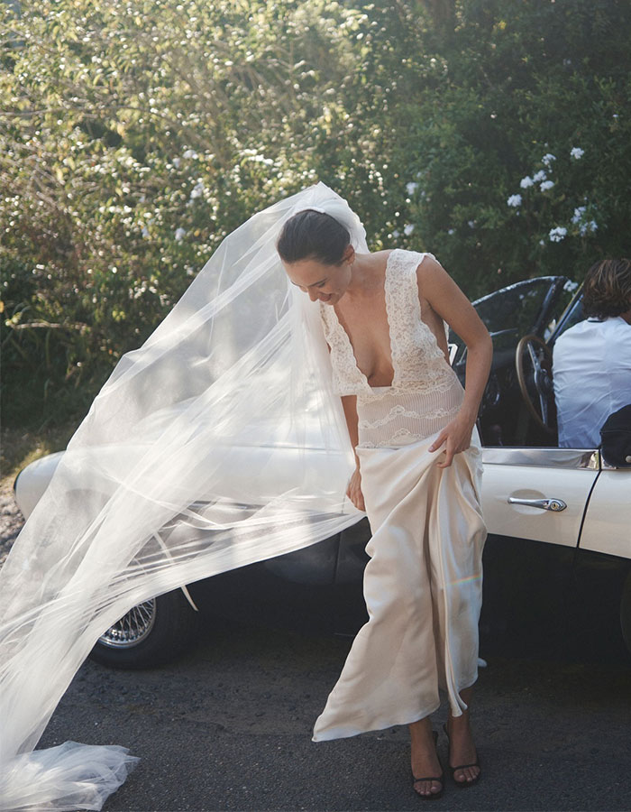Australian bride in a wedding dress with a lace top and flowing skirt, standing by a white car with her veil blowing in the wind. Australian bride in a wedding dress with a lace top and flowing skirt, standing by a white car with her veil blowing in the wind.