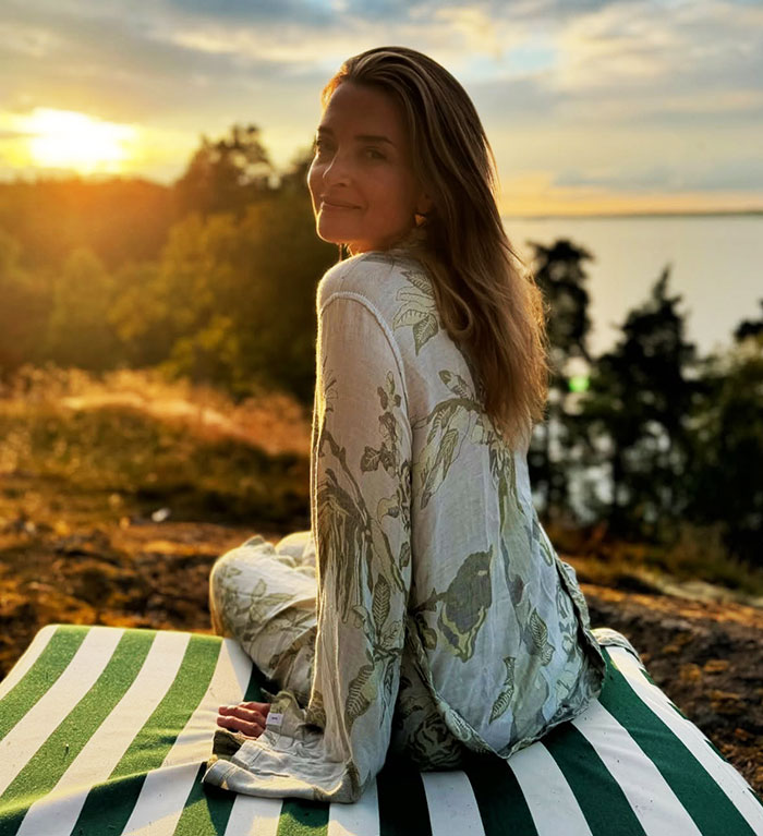 Woman sitting outdoors in nature during sunset, wearing a floral outfit. Woman sitting outdoors in nature during sunset, wearing a floral outfit.