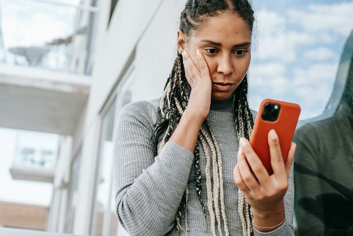 Woman looking concerned at phone, related to ex-friend tracking acquaintances. Woman looking concerned at phone, related to ex-friend tracking acquaintances.