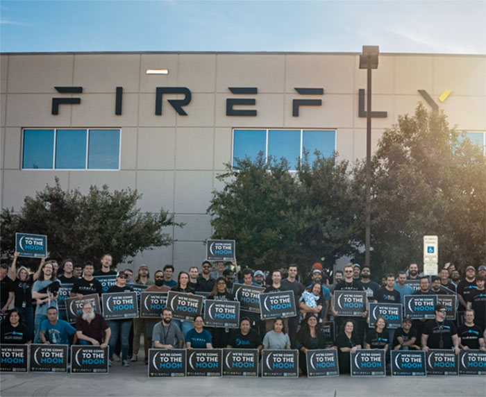 Group holding "To the Moon" signs in front of Firefly building, related to NASA's commercial robotic Moon launch. Group holding "To the Moon" signs in front of Firefly building, related to NASA's commercial robotic Moon launch.
