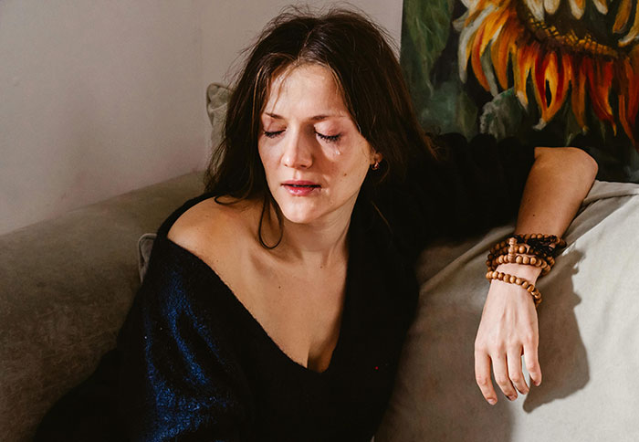 A woman looks upset on a couch, relating to a torched relationship. A woman looks upset on a couch, relating to a torched relationship.