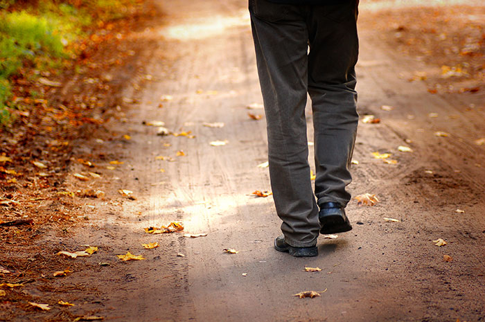 Person walking away on a leaf-strewn path, symbolizing being kicked out. Person walking away on a leaf-strewn path, symbolizing being kicked out.
