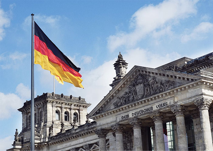 German flag waving outside the Reichstag building under a blue sky. German flag waving outside the Reichstag building under a blue sky.