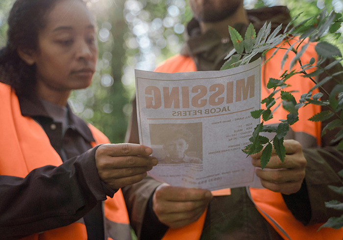 Search team members reviewing a missing person flyer in an outdoor setting. Search team members reviewing a missing person flyer in an outdoor setting.