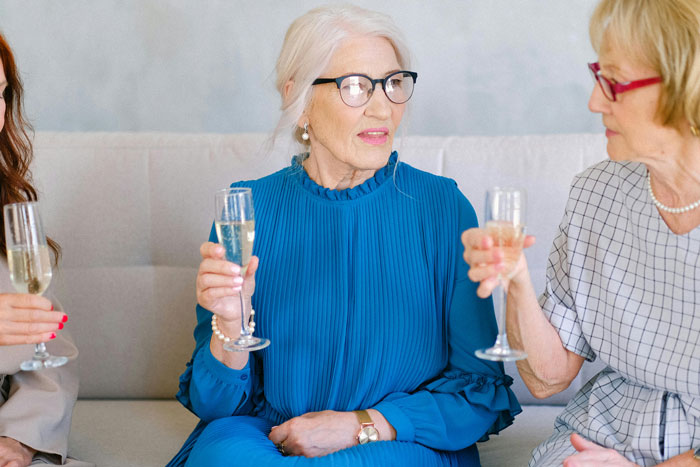 Elderly women at a rehearsal dinner, one in a blue dress, holding champagne. Elderly women at a rehearsal dinner, one in a blue dress, holding champagne.