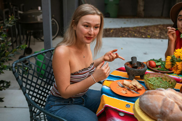 Woman at outdoor dinner, talking animatedly with food on a colorful table. Woman at outdoor dinner, talking animatedly with food on a colorful table.