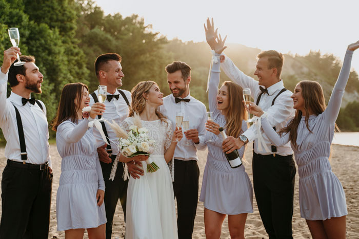 Wedding party celebrating outdoors with champagne, bride holding bouquet, smiling, surrounded by happy guests. Wedding party celebrating outdoors with champagne, bride holding bouquet, smiling, surrounded by happy guests.