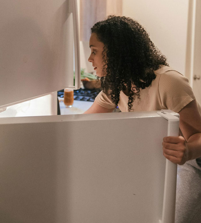 Woman looking inside a refrigerator, relating to food and roommates. Woman looking inside a refrigerator, relating to food and roommates.