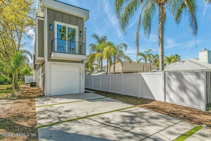 Small modern house with a garage in a Florida neighborhood, surrounded by palm trees. Small modern house with a garage in a Florida neighborhood, surrounded by palm trees.