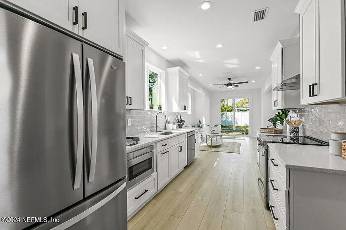 Modern kitchen in small Florida house with white cabinets, stainless steel appliances, and wood flooring. Modern kitchen in small Florida house with white cabinets, stainless steel appliances, and wood flooring.