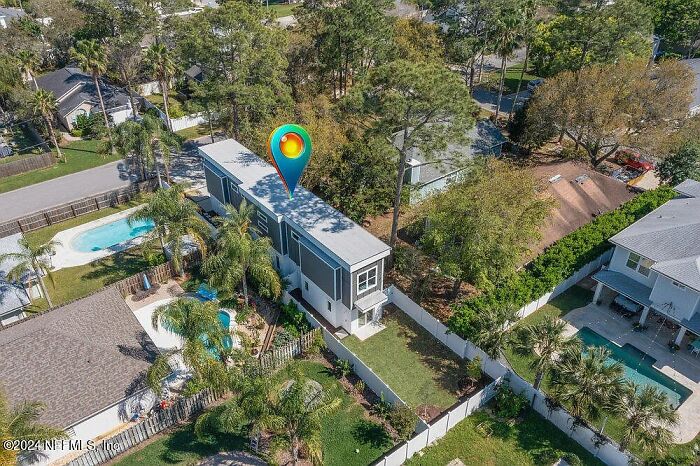Aerial view of a small modern house in a Florida neighborhood with a nearby pool and trees. Aerial view of a small modern house in a Florida neighborhood with a nearby pool and trees.