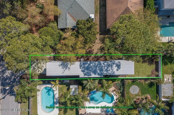 Aerial view of a small house in Florida with neighboring properties and a pool, surrounded by trees. Aerial view of a small house in Florida with neighboring properties and a pool, surrounded by trees.